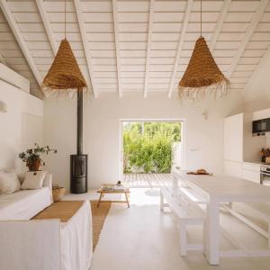 ein weißes Wohnzimmer mit einem Tisch und einem Sofa in der Unterkunft Casas de Arroz in Comporta