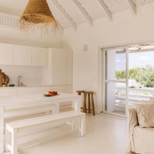 a white kitchen with a bench and a table at Casas de Arroz in Comporta