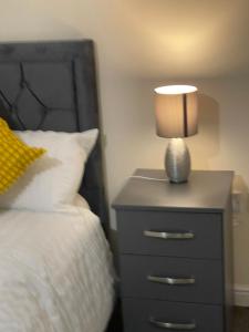 a nightstand with a lamp on it next to a bed at GM247 Nice Accommodation Stays in Wigan