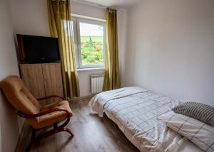 um quarto com uma cama, uma cadeira e uma janela em Domek Wilgówka em Jastrzębia