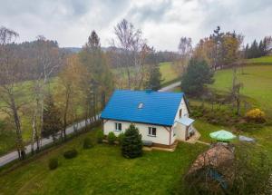 a house with a blue roof on a green field at Domek Wilgówka in Jastrzębia