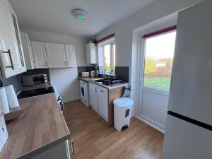 a small kitchen with white cabinets and a window at Frensham House in Dallington