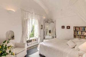 een witte slaapkamer met een bed en een raam bij GOCCE VILLAS - Green Coral Villa di lusso 1950 in Capri +30 foto's