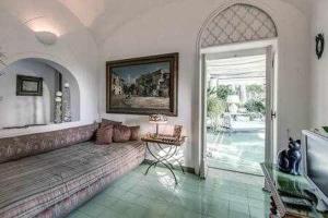 een woonkamer met een bank en een open deur bij GOCCE VILLAS - Green Coral Villa di lusso 1950 in Capri
