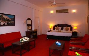 Habitación de hotel con cama y muebles de color rojo en Ibri Oasis Hotel en ‘Ibrī