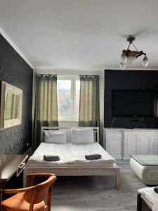 um quarto com uma cama branca e uma televisão em AtmosferA em Bydgoszcz