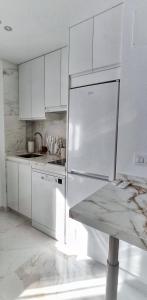 uma cozinha com armários brancos e um frigorífico de aço inoxidável em Apartamento CENTRO, La Palmera. em Huelva