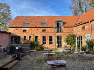 BoitzenburgにあるGasthof zum grünen Baumのレンガ造りの建物で、目の前にテーブルと椅子があります。