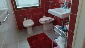 a red bathroom with a toilet and a sink at A 2 passi da tutto in Trapani