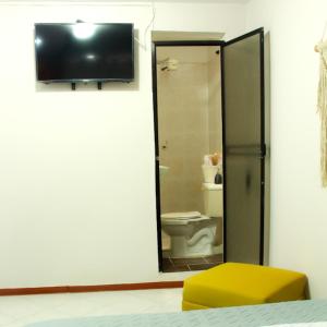 a bathroom with a toilet and a television on a wall at Casa Mostaza in Medellín
