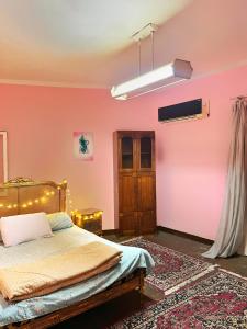 um quarto com uma cama e uma parede rosa em Cozy room in the heart of cairo no Cairo