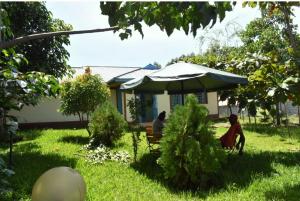 twee mensen zitten op een bank onder een paraplu in een tuin bij D'LUX HOME RODI KOPANY in Homa Bay