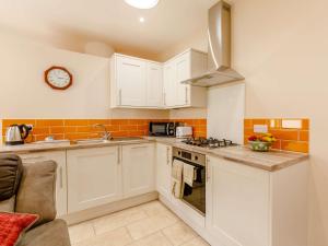 a kitchen with white cabinets and a clock on the wall at 1 Bed in South Molton 89089 in South Molton