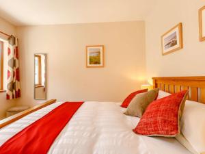 a bedroom with a large bed with red pillows at 1 Bed in South Molton 89089 in South Molton