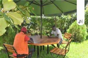 twee mannen aan een tafel onder een paraplu bij D'LUX HOME RODI KOPANY in Homa Bay
