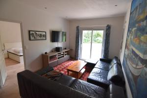 een woonkamer met een zwarte leren bank en een televisie bij Vacances familiales a Erquy in Erquy
