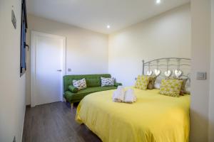 um quarto com uma grande cama amarela e um sofá verde em RentitSpain Las Fanegas Montañas de Alpujarra em Yátor
