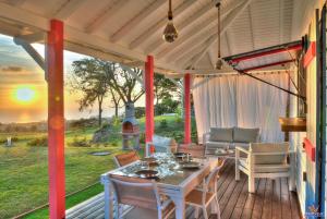 eine abgeschirmte Veranda mit einem Tisch und Stühlen in der Unterkunft Le Domaine de l'Ilet in Saint-Claude