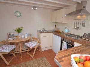 a kitchen with a table and chairs and a table and a bowl of fruit at 1 Bed in Torrington 42982 in Petrockstow