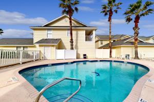 a swimming pool in front of a house with palm trees at Beach Haven Unit 201 in Corpus Christi
