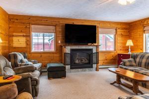 sala de estar con chimenea y TV de pantalla plana en Lake Manistee Lodge Ski & Snowmobile Hideout, en Kalkaska