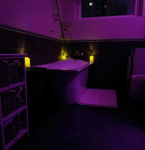 Baño púrpura con bañera y alfombra en Skanstes Virsotnes Flying Bed Apartment (Skanstes Heights), en Riga
