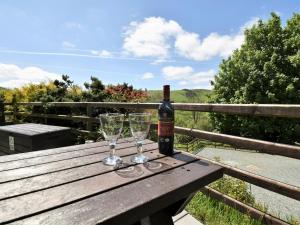 a bottle of wine and two glasses on a wooden table at 1 Bed in Rhayader 45386 in Llangurig