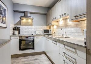 a kitchen with white cabinets and a sink at The Studio @ No. 6 in Brimscombe