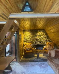 Habitación con pared de piedra, sofá y mesa. en yuvacik kazli bahçe bungalov & taş otel, en Yuvacık