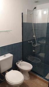a bathroom with a toilet and a glass shower at Departamentos Don Claudio in San Luis