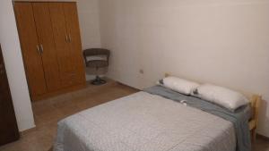 a bedroom with a bed with two pillows and a chair at Departamentos Don Claudio in San Luis