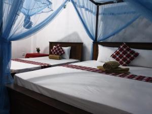 two beds in a bedroom with blue drapes at Shasee Rest-Mirissa in Mirissa