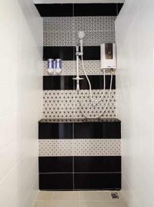 La salle de bains est pourvue d'une douche avec du carrelage noir et blanc. dans l'établissement The Guest Hotel & Hostel, à Chiang Mai