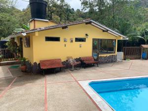 Casa amarilla con bancos y piscina en Casa Campo Piscina jacuzzi turco sauna El Encanto, en San Francisco