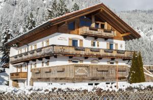 una casa di tronchi con balcone nella neve di Gästehaus Münchner Kindl a Reit im Winkl