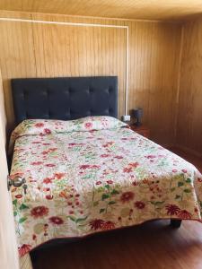 1 dormitorio con 1 cama con colcha de flores en Cabaña rio cululi, sector Pocoihuen alto, en Cochamó