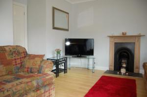 sala de estar con sofá y TV de pantalla plana en Netherleigh Family Bungalow in Pennal, en Pennal