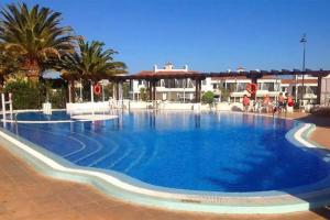 una gran piscina azul con palmeras y edificios en Oasis Retreat 793 - Appartamento con piscina a Amarilla Golf, en San Miguel de Abona