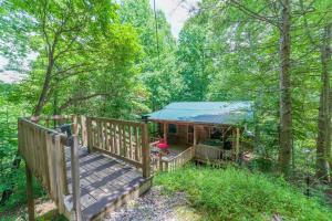 a cabin in the woods with a wooden deck at Couples Getaway Cabin near National Park w Hot Tub in Pigeon Forge