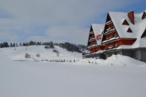 ビャウカにあるCzerwone Wierchy - sauna i jacuzzi wliczone w cenę podczas pobytu!の山の隣の雪に覆われた建物