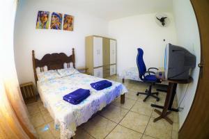 Schlafzimmer mit einem Bett, einem TV und einem Schreibtisch in der Unterkunft Casa Central em Pará de Minas in Pará de Minas