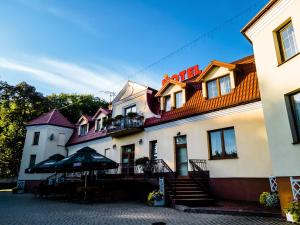 un bâtiment avec un parasol devant lui dans l'établissement Hotel Pałacowa, à Narol