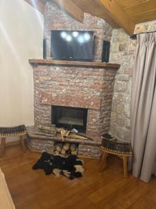 a living room with a stone fireplace with a flat screen tv at Hotel Ambassador Voskopojë in Voskopojë