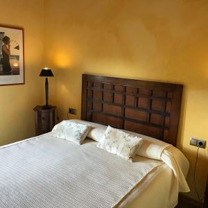 1 dormitorio con 1 cama grande con sábanas y almohadas blancas en Hotel Villaro Del Bosc, en Freixinet