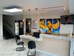 a lobby with a bar with chairs and paintings on the wall at HOTEL FÊNIX in Campina Grande