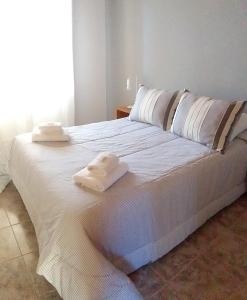 Una cama blanca con dos toallas encima. en La Pausa en Carhué