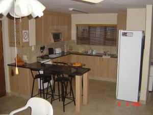 a kitchen with a table and a white refrigerator at Toch Noch in Hartenbos