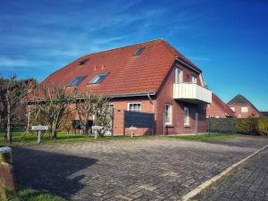 ネスマージールにあるNessmersiel, Renovierte Erdgeschosswohnung mit Garten, in Deichnähe, Wallbox,の赤い屋根の大きなレンガ造りの家