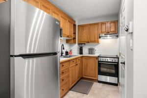 a kitchen with wooden cabinets and a stainless steel refrigerator at Mountain Retreat in North Saanich