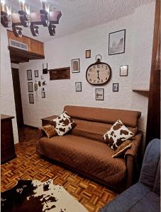 uma sala de estar com um sofá e um relógio na parede em CHALET LAVANDA San Giacomo di roburent em San Giacomo